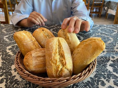 Tanınmayan bir adam restoran masasındaki bir sepet ayrı somundan bir somun ekmek alıyor.