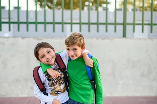 Dos Niños Con Mochilas Espalda Abrazan Mirando Cámara Regreso Concepto — Foto de Stock
