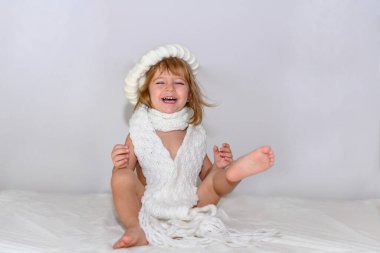 Kız yüksek sesle gülüyor, büyük beyaz bir kış beresi ve eşarbı takıyor..