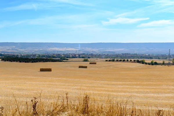Landscape of plowed field with squares of straw in the background industrial zone in Villanueva de la Torre a town in Guadalajara Spain