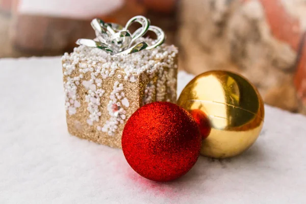 Bolas de Natal vermelho brilhante e ouro com um presente de brinquedo na neve — Fotografia de Stock