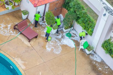 İşteki bir temizlik ekibi bir apartman dairesi veya otelin havuzunun bakımını ve düzenlenmesini sağlıyor.