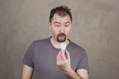 Duygular. Enerji tasarrufu lambası ve aleti olan bir adam.