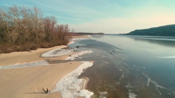 Images aériennes de drones survolant un rivage sablonneux avec une petite rivière en hiver — Video