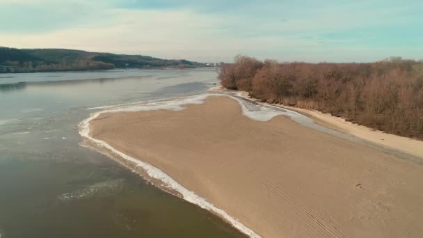 Aerial drone footage of flight over a sandy shore with a small river in winter — Stok video