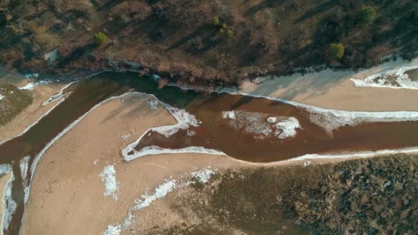 Aerial drone footage of flight over a small river in winter top-down view. — Stockvideo