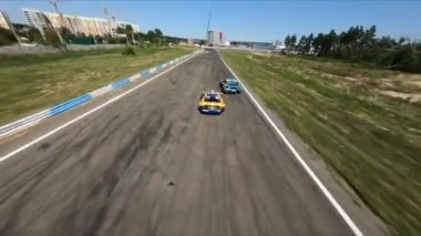 FPV İHA yarışmada iki drift arabayı kovalıyor.