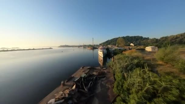 FPV drone vista di volare sopra l'acqua all'alba oltre una nave abbandonata — Video Stock