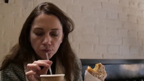 Mladá žena jíst vynikající pečený croissant a pít čaj v kavárně. — Stock video