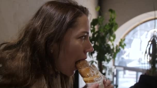 Jonge vrouw eten heerlijk gebakken croissant in cafe. — Stockvideo