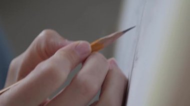 The hand of a young girl draws with a pencil on canvas. High quality FullHD footage