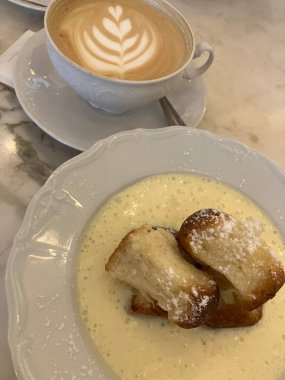 Bir fincan kahveyi krema, kaşık ve çörekle kapat.