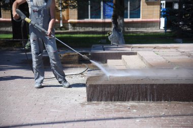 Bir işçi, basınç altında betondan kiremitleri suyla yıkar..