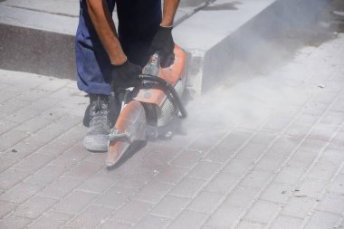 Bir işçi dairesel testere ile sıralanmış döşeme levhaları kesiyor, bir sürü toz..