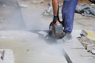 Bir işçi inşaat alanında asfaltı dairesel testereyle keser, otoyol inşaatında..