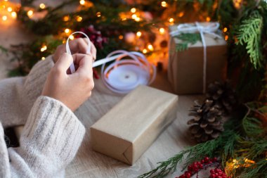 Noel konsepti, kadın eli hediye paketi masa üzerinde dekor ve çelenk, yakın plan..