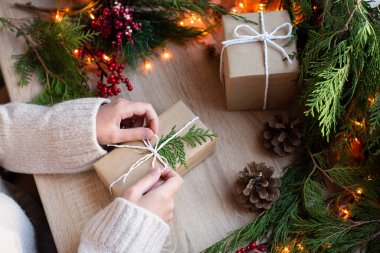 Kadın eli hediye paketi masanın üstünde dekor ve çelenk, Noel konsepti, yakın plan..