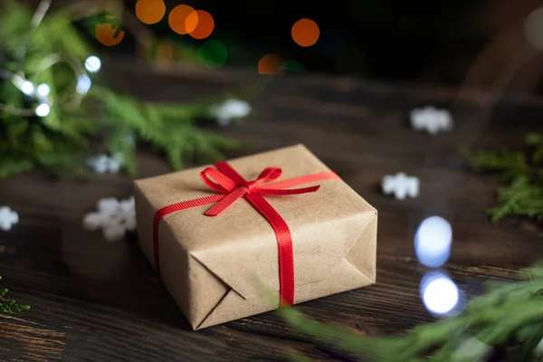 Tatil konsepti, el sanatları kağıdında noel hediyesi, ahşap masada mevcut ve arka plan aydınlık, yakın plan..