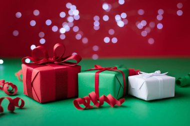 Kırmızı ve yeşil arka planda üç hediye, yılan ve ışık bokeh, Tatil ve Noel arka planı, yakın plan.