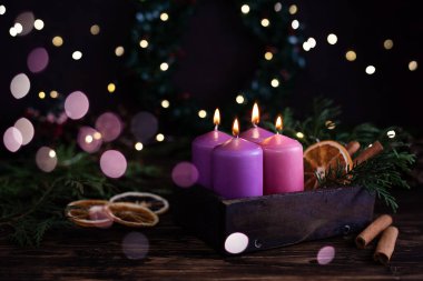 Dört mor yanan mum, koyu ahşap arka planda, şenlikli bokeh ışıkları, Noel arifesi..