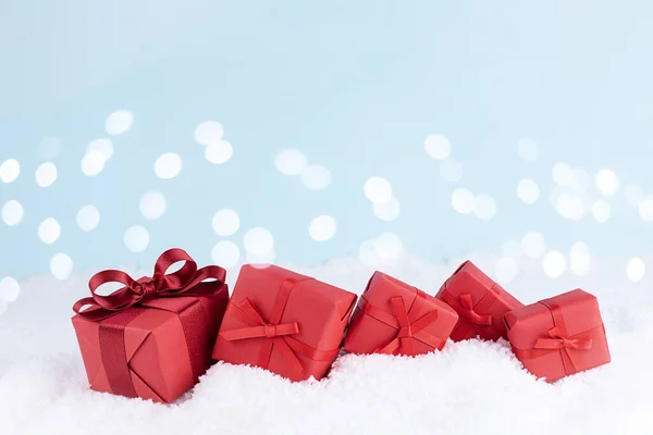 Noel konsepti, kış tatilleri için hediye, karda bokeh lambalı kırmızı hediyeler, kopyalama alanı.