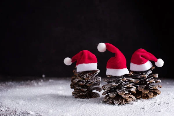 Šišky Santa Claus Klobouky Podobě Vánočního Stromečku Sněhu Tmavém Pozadí — Stock fotografie