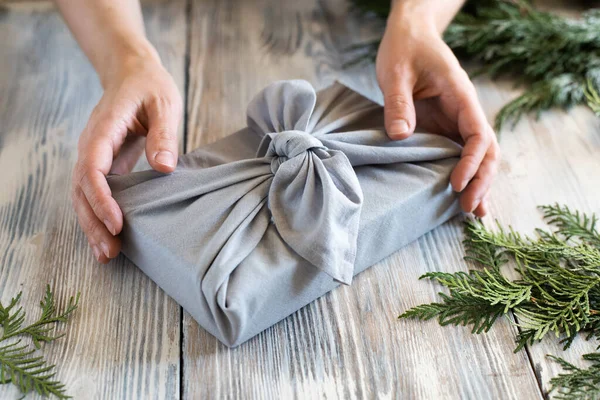 Tangan Wanita Memegang Hadiah Natal Yang Dibungkus Kain Dengan Latar — Stok Foto