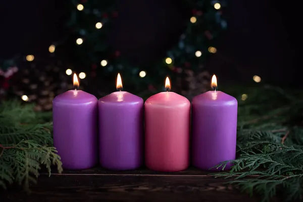 나무로 크리스마스 배경에 가시와 화환이 불타는 보라색 촛불이 줄지어 로열티 프리 스톡 사진