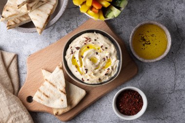 Humus, zeytinyağlı, pide ekmekli gri arka planda, sebze soslu ve abur cuburlu..