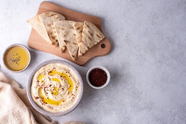 Sebze sosu ve atıştırmalık, zeytinyağlı humus ve beyaz arka planda kesilmiş bir tahtada pita ekmeği..