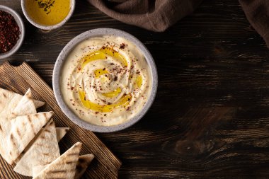Nohut humus kasesi, koyu ahşap arka planda baharatlar ve pide, vejetaryen sebze yemeği, sağlıklı beslenme..
