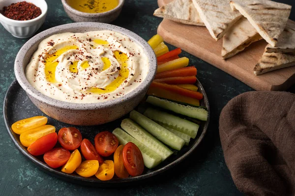 Dilimlenmiş sebze ve sebzeli kase, yeşil arka planda humus ve pide, sağlıklı vejetaryen atıştırmalığı..
