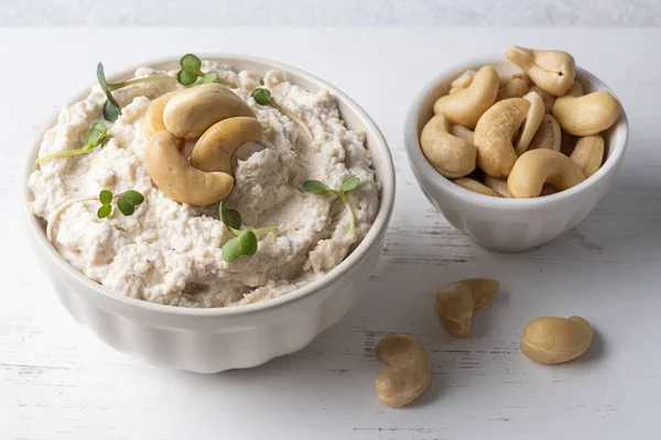 Mayalanmış fındıktan yapılmış alternatif peynir, beyaz bir masada kaju peynirli kase, sağlıklı beslenme..