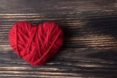 DIY yarn red heart on a dark wooden background, a symbol of love for Valentine's Day.