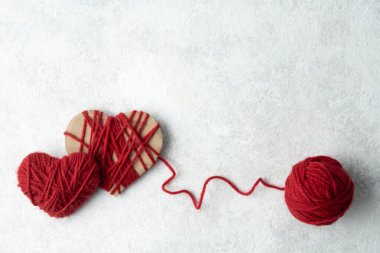 Two hearts made of red woolen yarn and a ball of thread on a white background, Valentine's day concept.
