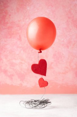 Red balloon and two red hearts on a pink background, Valentine's day concept.