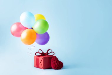 Multicolored balloons, heart, gift on a blue background, Valentine's Day and birthday concept.