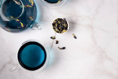 Cam çaydanlık ve fincanda kelebek bezelyesinden mavi çay mermer arka planda, üst manzara..