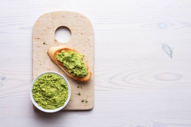 Guacamole ile kase, beyaz arka planda kızarmış ekmeğin üzerine yayılmış avokado..