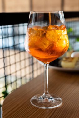 A glass of aperol with ice cubes, an alcoholic drink on a table in a restaurant, a cocktail, close-up .