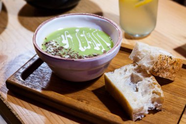 Cream soup of green peas with slices of bread on the table in the restaurant, vegetarian healthy food.