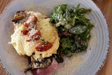 Scrambled eggs, ham and tomato on toasted bread, leafy vegetable salad, breakfast sandwich, close-up.