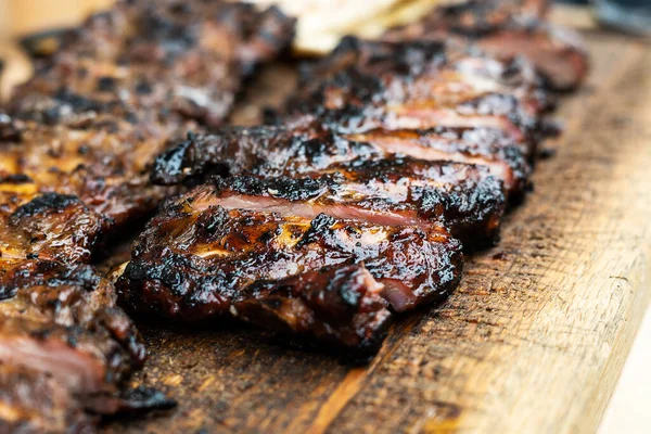 Grilled and smoked pork ribs, barbeque spare ribs on wooden cutting board, close-up.