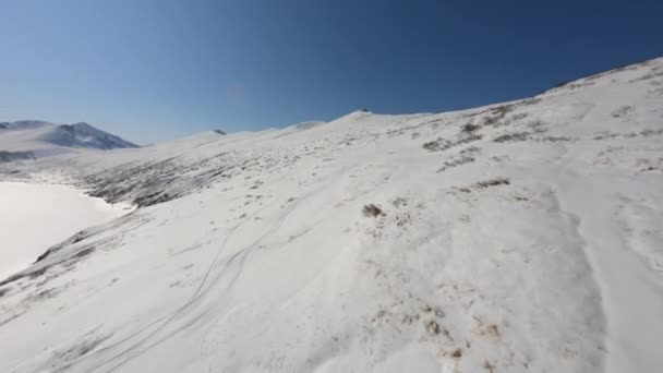 Letecký fpv drone filmový pohled létající nad malebným zasněženým horským terénem obklopený vrcholky útesů — Stock video