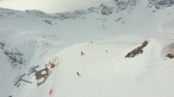 Vue aérienne sport FPV drone plongée de la falaise et suivant au skieur féminin — Video