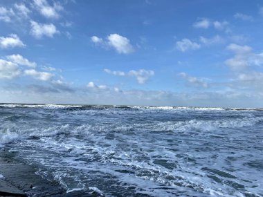 Gün boyunca dalgalar mavi gökyüzüne karşı kıyıda dalgalar. Köpük dalgaları.