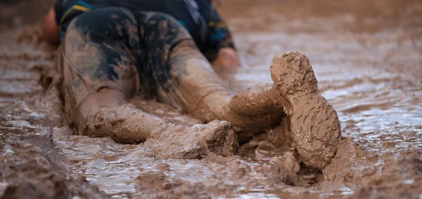 泥巴赛跑选手 在极限运动中 在铁丝网障碍物下爬行通过 把重点放在鞋子上 — 图库照片