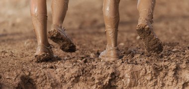 Çamur koşucuları bacakların ayrıntıları çamurlu koşu ayakkabıları çamurda bir koşu