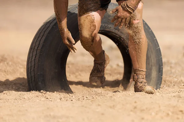Çamur yarışçıları. Katılımcı, lastik yarışının önündeki engelleri aşıyor.