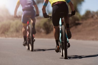 Çiftler ormanda asfalt bir yolda bisiklet sürerler, gündoğumu sağlıklı yaşam tarzı aktif sporculardır.